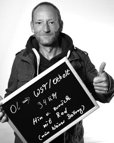 Eine Person aus Oldenburg zeigt ein Schild auf dem steht „OL - WST/Ocholt, 34 Kilometer hin und zurück mit Rad (mein kleiner Beitrag)“ Foto: Jörg Hemmen