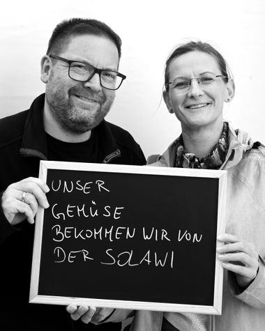 Zwei Personen aus Oldenburg zeigen ein Schild auf dem steht „Unser Gemüse bekommen wir von der Solawi“ Foto: Jörg Hemmen