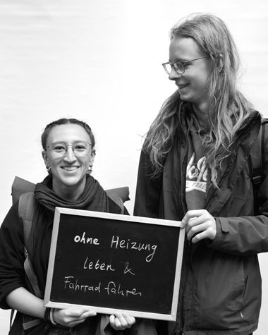 Zwei Personen aus Oldenburg zeigen ein Schild auf dem steht „ohne Heizung leben und Fahrrad fahren“ Foto: Jörg Hemmen