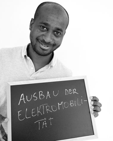 Eine Person aus Oldenburg zeigt ein Schild auf dem steht „Ausbau der Elektromobilität“ Foto: Jörg Hemmen