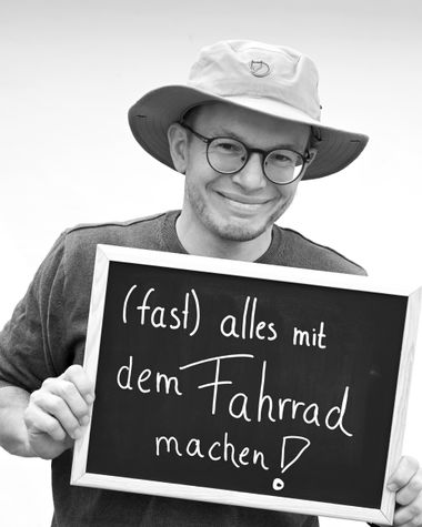 Eine Person aus Oldenburg zeigt ein Schild auf dem steht „(Fast) Alles mit dem Fahrrad machen!“ Foto: Jörg Hemmen
