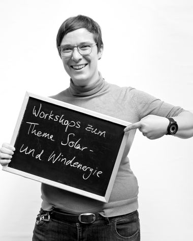 Eine Person aus Oldenburg zeigt ein Schild auf dem steht „Workshops zum Thema Solar- und Windenergie“ Foto: Jörg Hemmen