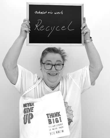 Eine Person aus Oldenburg zeigt ein Schild auf dem steht: „Schmiet nix wech: Recycel!“ Die Person hat eine selbst gestalteten Beutel um den Hals. Foto: Jörg Hemmen