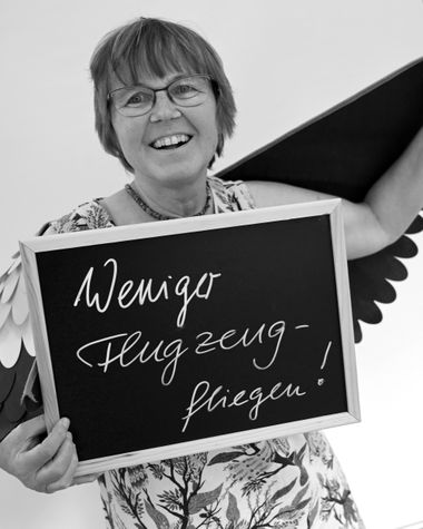 Eine Person aus Oldenburg zeigt ein Schild auf dem steht: „Weniger Flugzeug fliegen!“ Foto: Jörg Hemmen
