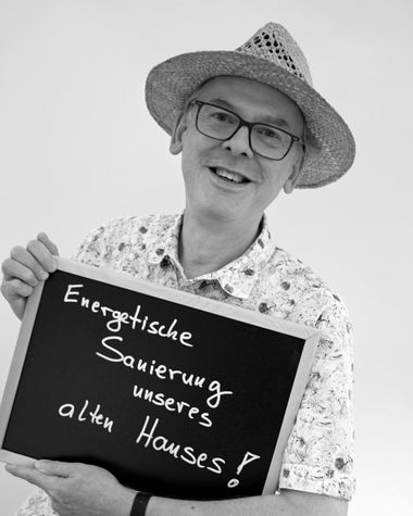 Eine Person aus Oldenburg zeigt ein Schild auf dem steht: „Energetische Sanierung unseres alten Hauses!“ Foto: Jörg Hemmen