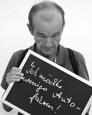 Eine Person aus Oldenburg zeigt ein Schild auf dem steht „Ich möchte weniger Auto fahren!“ Foto: Jörg Hemmen