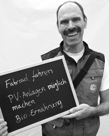 Eine Person aus Oldenburg zeigt ein Schild auf dem steht „Fahrrad fahren, PV-Anlagen möglich machen, Bio-Ernährung“ Foto: Jörg Hemmen