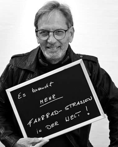 Eine Person aus Oldenburg zeigt ein Schild auf dem steht „Es braucht mehr Fahrrad-Straßen in der Welt!“ Foto: Jörg Hemmen