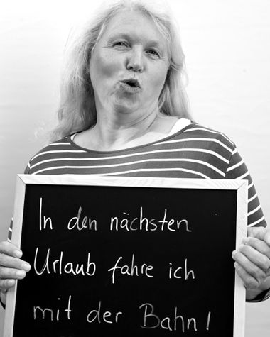 Eine Person aus Oldenburg zeigt ein Schild auf dem steht „In den nächsten Urlaub fahre ich mit der Bahn!“ Foto: Jörg Hemmen