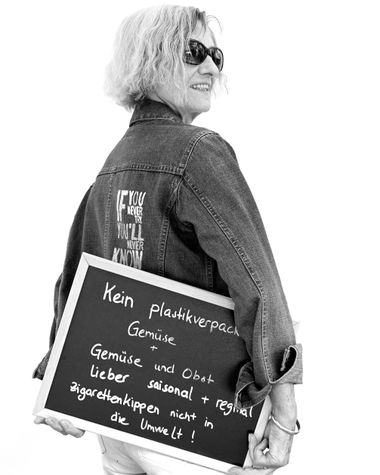 Eine Person aus Oldenburg zeigt ein Schild auf dem steht: „Kein plastikverpacktes Gemüse und Gemüse und Obst lieber saisonal und regional. Zigarettenkippen nicht in die Umwelt!“ Foto: Jörg Hemmen