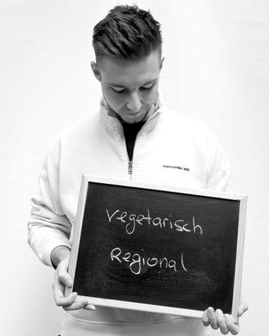 Eine Person aus Oldenburg zeigt ein Schild auf dem steht „vegetarisch regional“ Foto: Jörg Hemmen