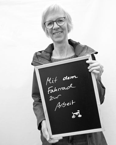 Eine Person aus Oldenburg zeigt ein Schild auf dem steht „Mit dem Fahrrad zur Arbeit“ Foto: Jörg Hemmen