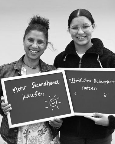 Zwei Personen aus Oldenburg zeigen ein Schild auf dem steht „Mehr Secondhand kaufen und öffentlichen Nahverkehr nutzen“ Foto: Jörg Hemmen