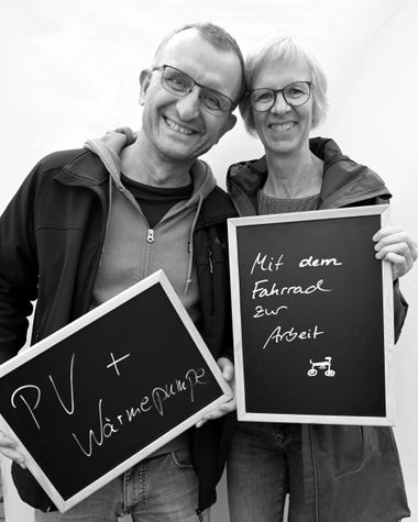 Zwei Personen aus Oldenburg zeigen jeweils ein Schild auf denen steht „PV und Wärmepumpe“ und „Mit dem Fahrrad zur Arbeit“ Foto: Jörg Hemmen