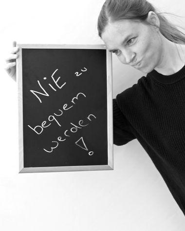 Eine Person aus Oldenburg zeigt ein Schild auf dem steht „Nie zu bequem werden!.“ Foto: Jörg Hemmen