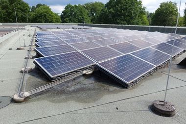 Photovoltaikanlage auf einem Flachdach, im Hintergrund sind grüne Bäume zu sehen. Foto: Stadt Oldenburg