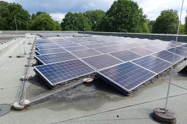 Photovoltaikanlage auf einem Flachdach, im Hintergrund sind grüne Bäume zu sehen. Foto: Stadt Oldenburg