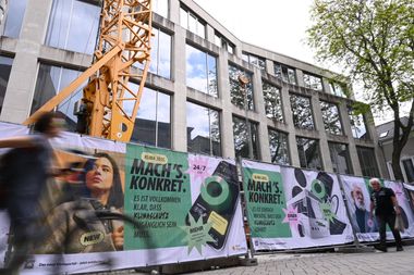 Banner an einem Bauzaun vor einem Haus mit „Mach's. Konkret“-Kampagne