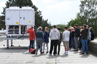 Zu sehen ist eine Gruppe Menschen, die vor einer Großwärmepumpe auf einem Dach stehen und Informationen dazu erhalten. Foto: Jörg Hemmen