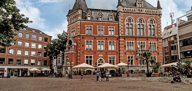 Oldenburger Rathaus und ein paar Menschen auf dem Marktplatz. Foto: Mittwollen und Gradetchliev