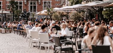 Am Marktplatz in Oldenburg sitzen Menschen in den Cafés. Foto: Mittwollen und Gradetchliev