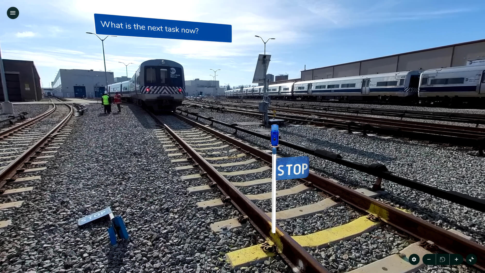 Train yard with tracks labeled "STOP." Two workers are near a train. A blue banner reads, "What is the next task now?"