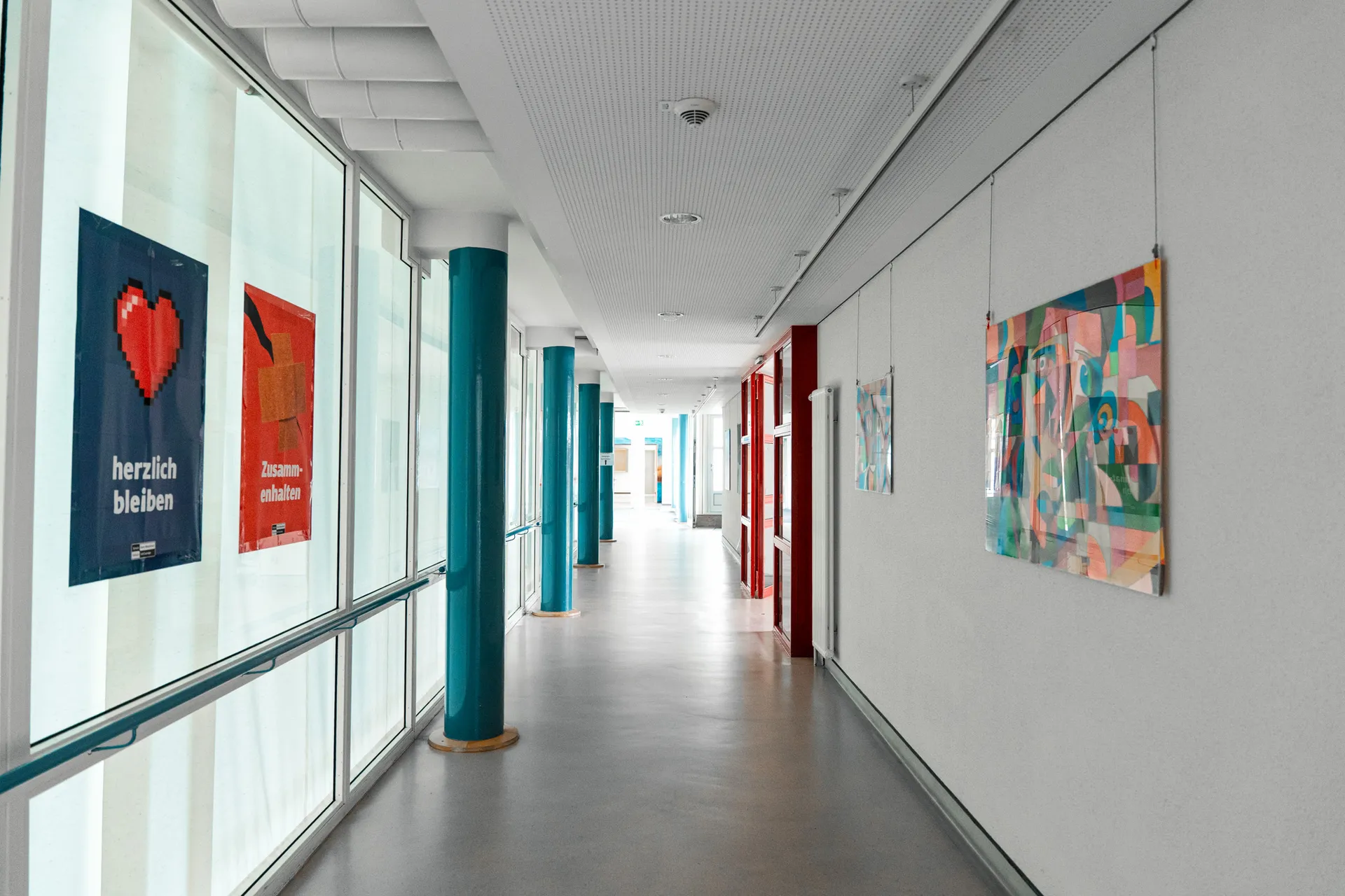Oberlinhaus Freudenstadt – Ausbildung zum/zur Fachpraktiker/-in für Reinigungstechnik: Heller, sauberer Flur mit großen Fenstern, farbigen Säulen und Wandbildern.