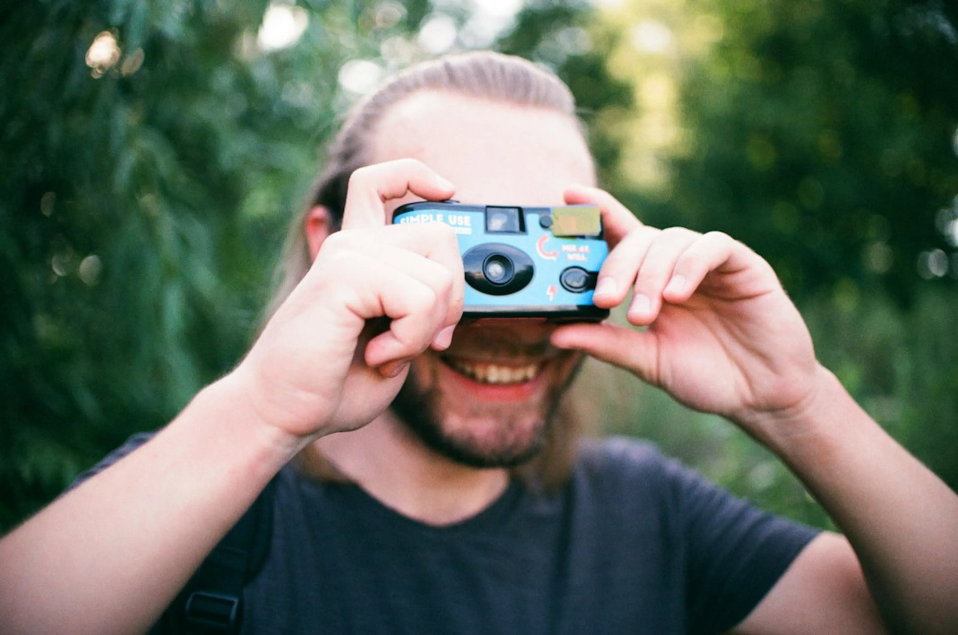 A guest laughing behind a single-use camera held up to take a photo