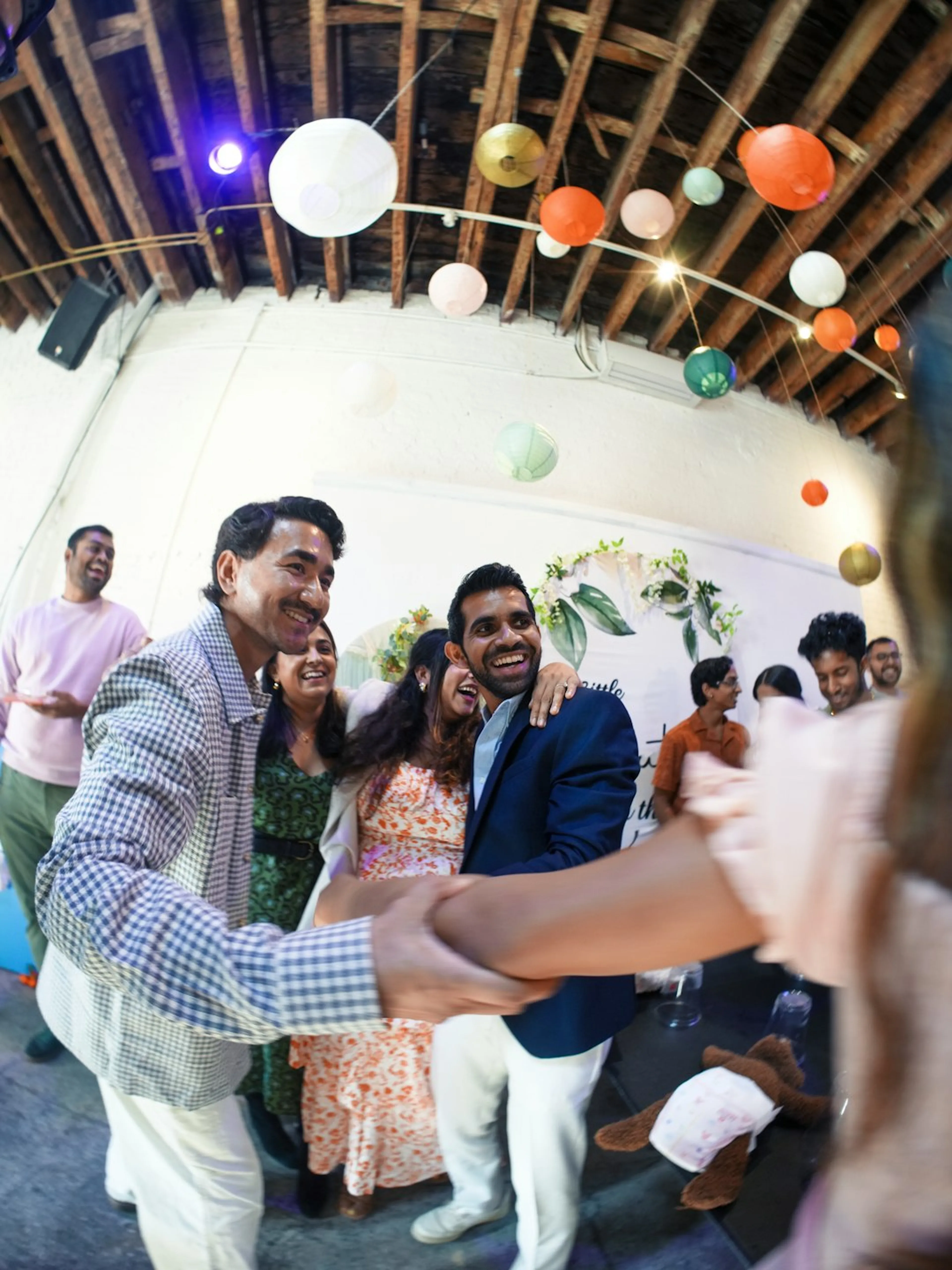 Wedding guests dancing together under paper lanterns at the reception