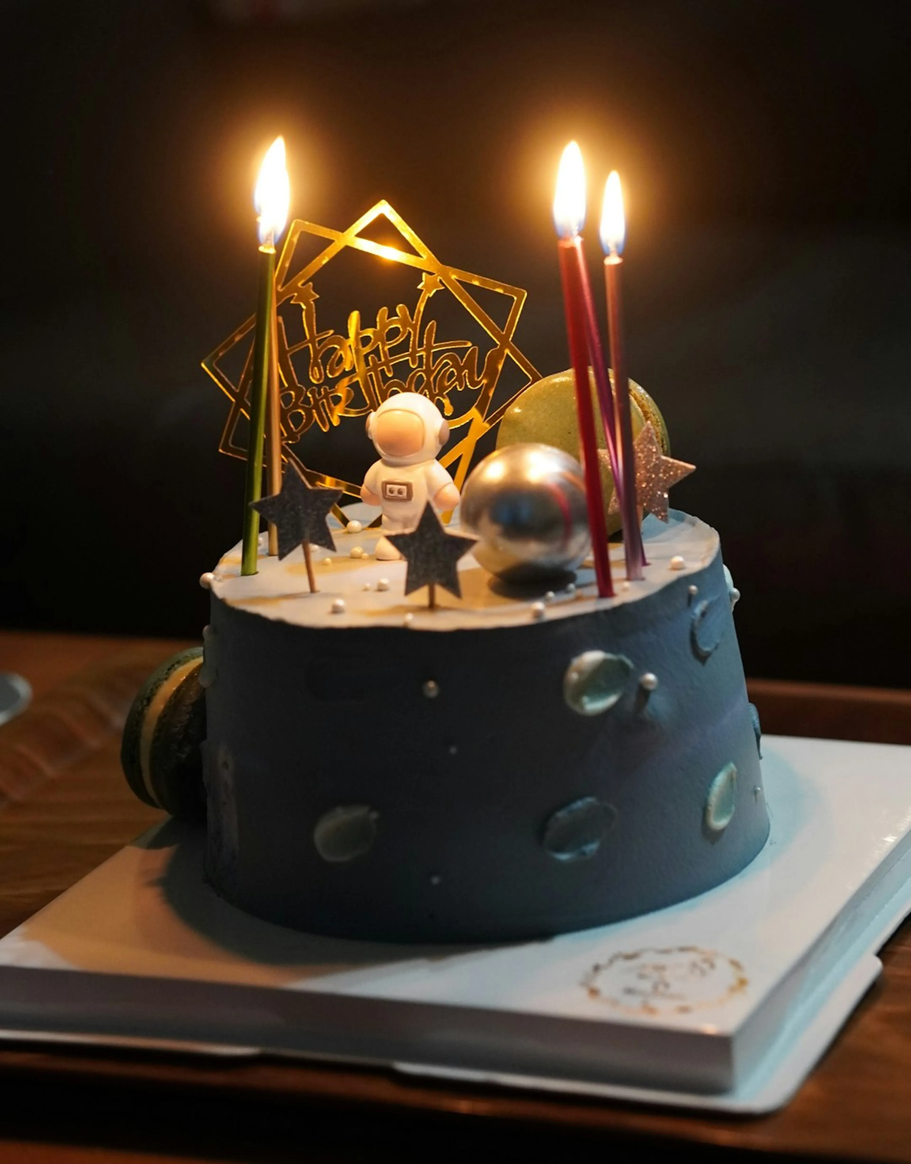 A birthday cake with lit candles and a happy birthday topper