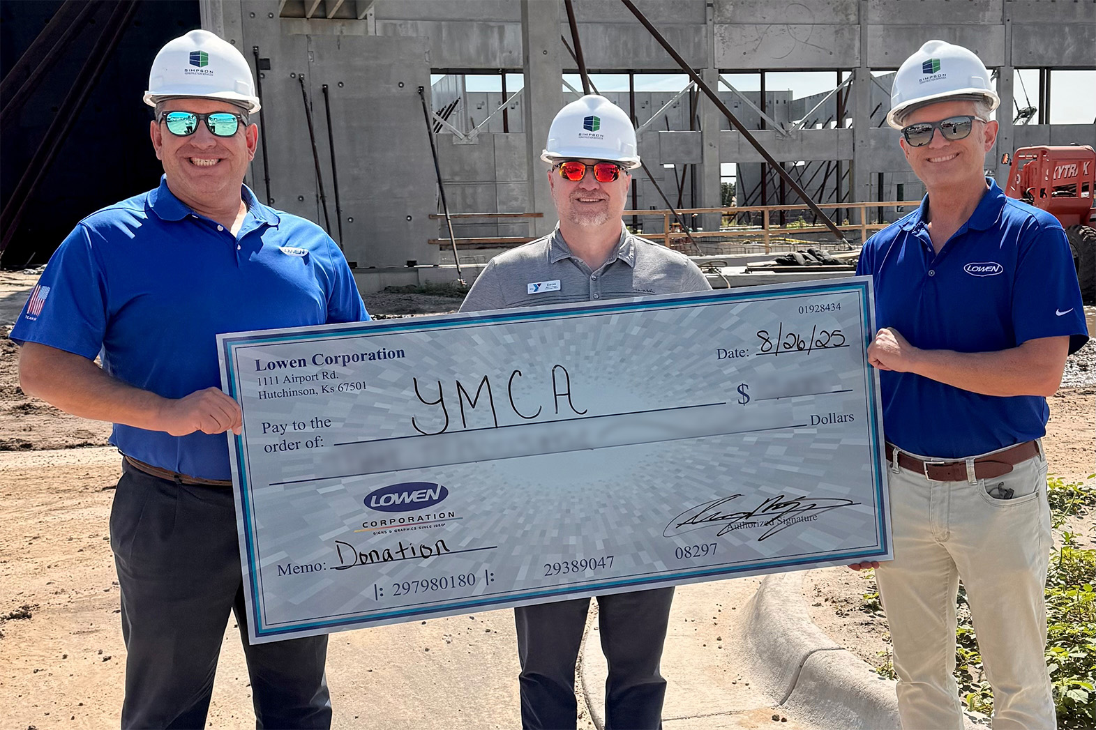 Lowen Corporation representatives present a donation check to the Hutchinson YMCA at the construction site for the new facility in Hutchinson, Kansas.