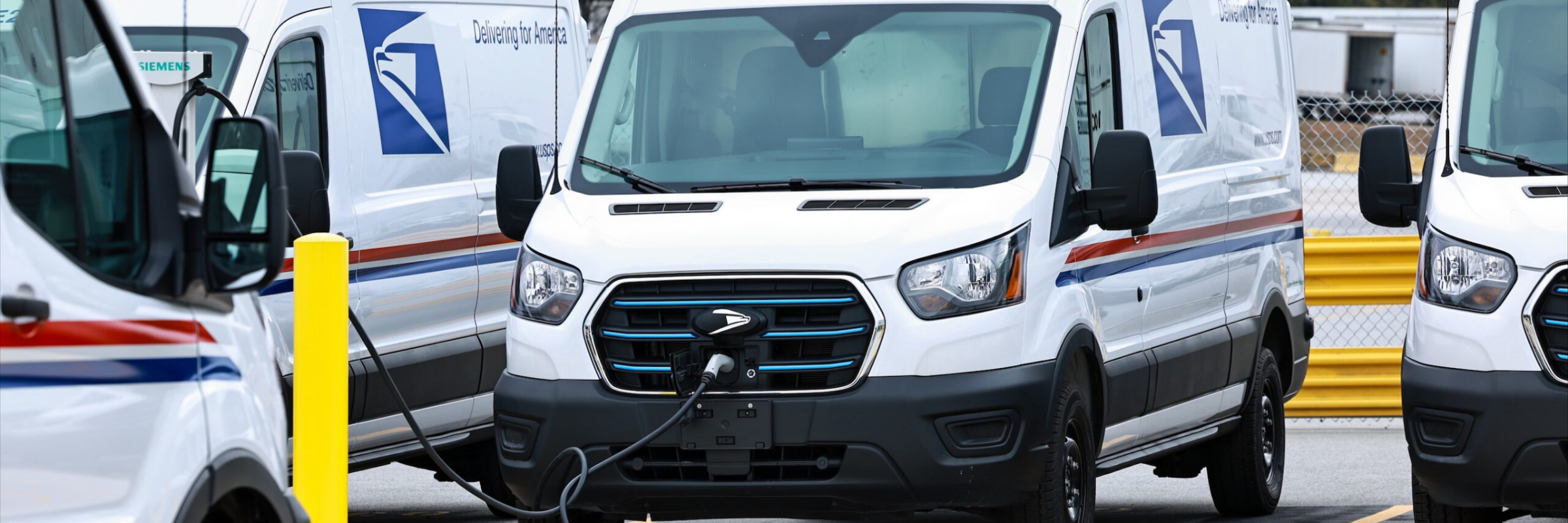 USPS electric delivery vans with fleet graphics charge at the South Atlanta Sorting and Delivery Center during the 2024 EV fleet launch.
