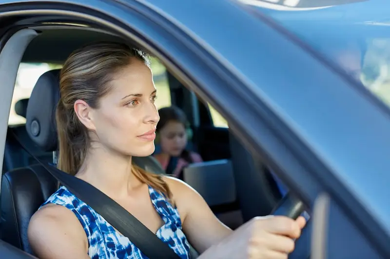 Woman driving with child on back seat