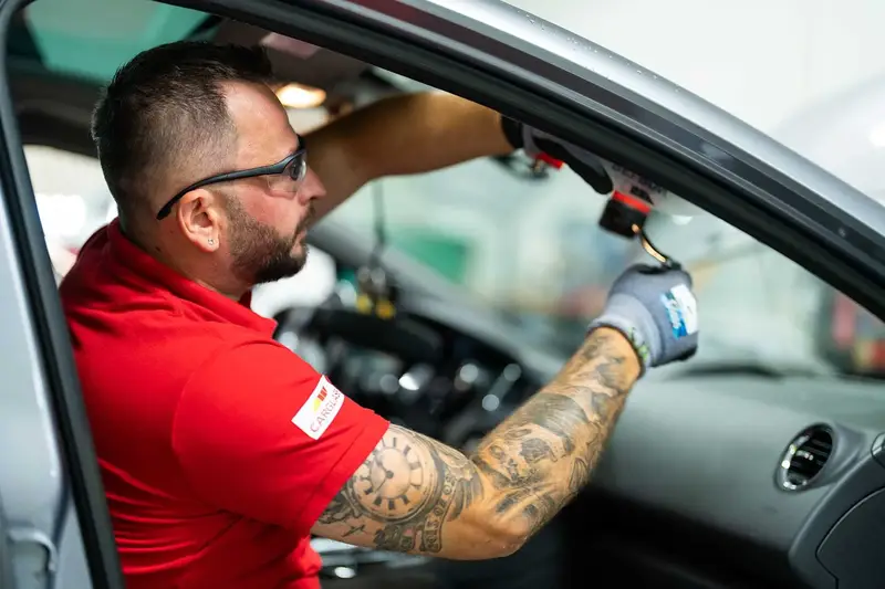 Tekniker lagar stenskott i vindruta inifrån bilen