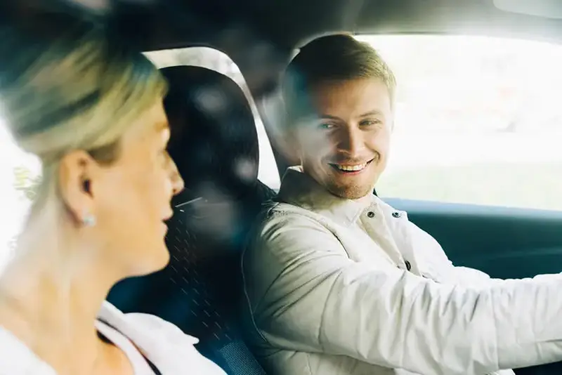 Man and woman on car smiling