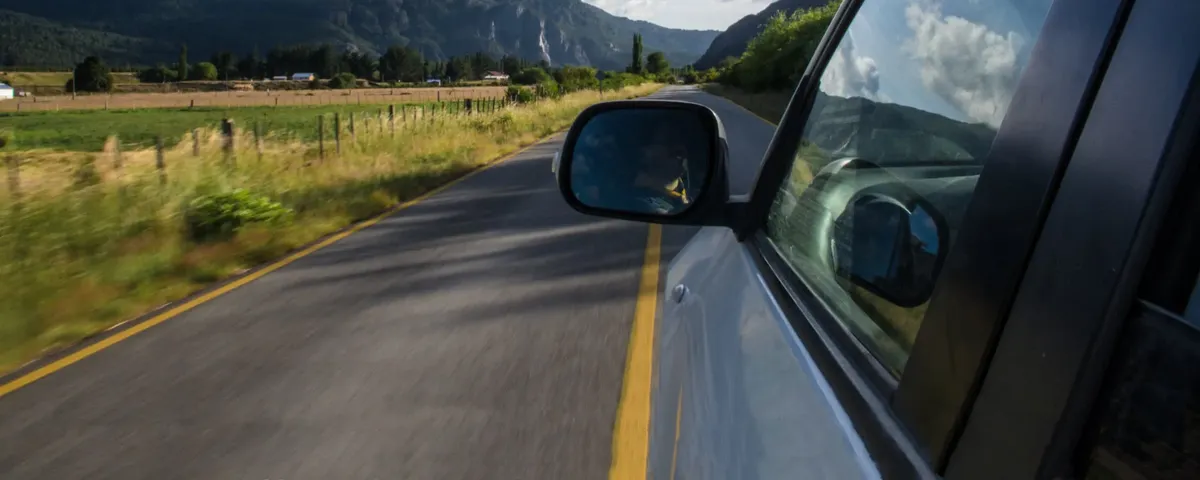 Windscreen side mirror view on road