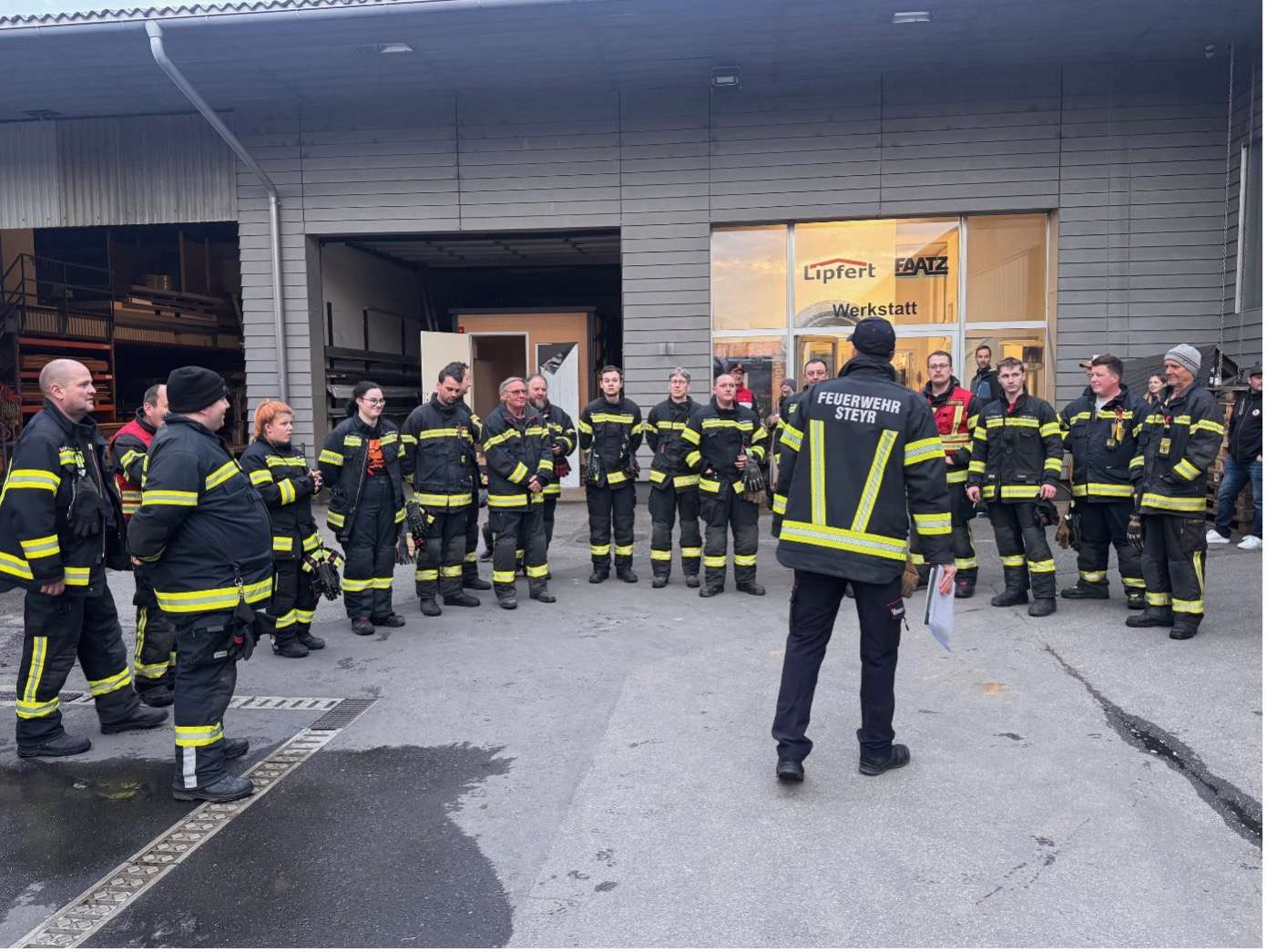 Mehrerer Frauen und Männer in Feuerwehrkleidung vor dem Lipfert und Faatz Gebäude.