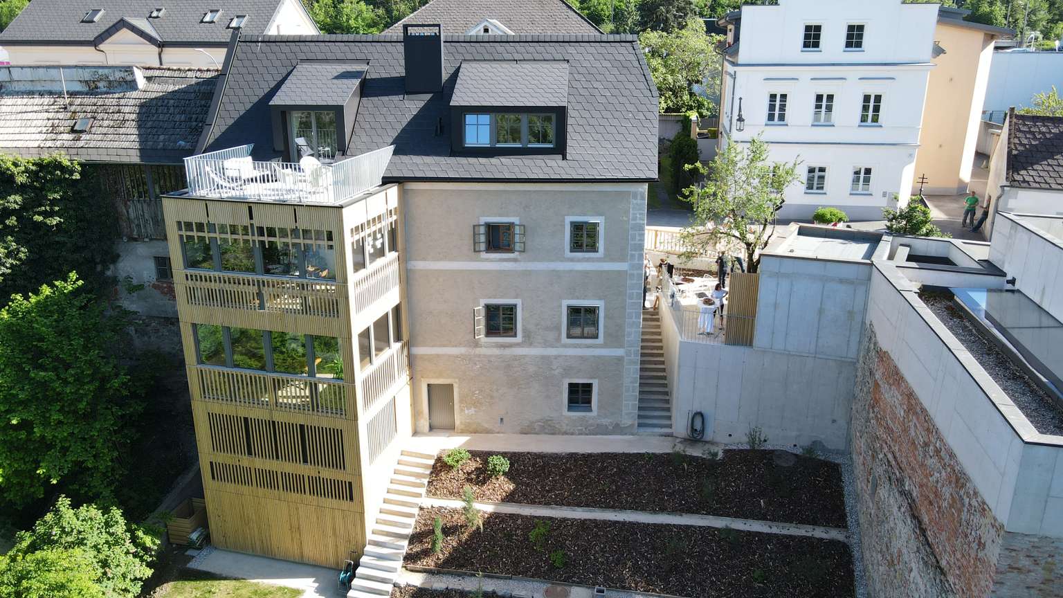 Außenansicht des Flößerhaus nach der Fertigstellung mit Holzvorbau und Erdfläche beim Treppenabgang.