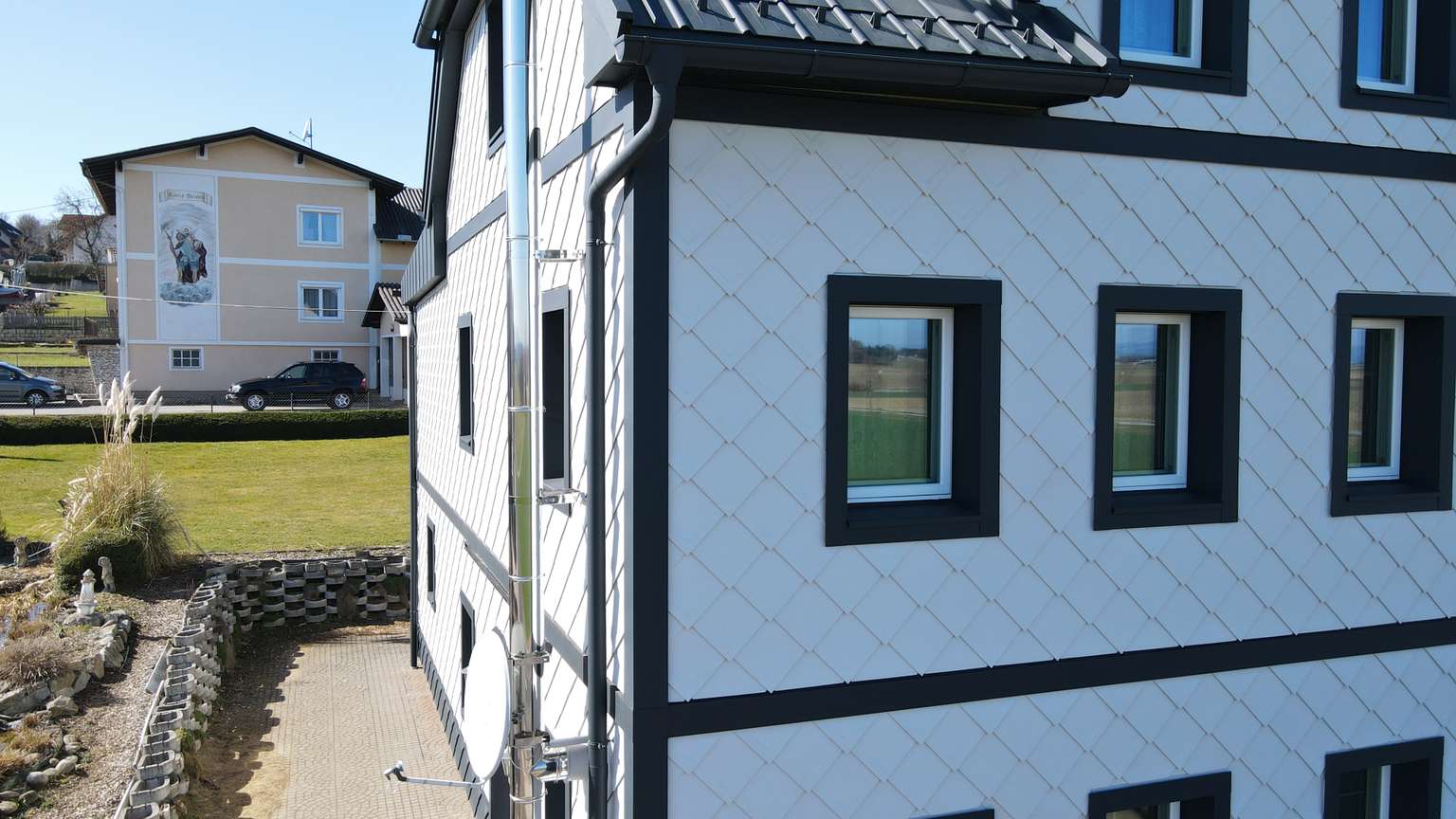 Eckansicht der verzierten Fassade mit schwarz umrandeten Fenstern und Gebäudeecken.