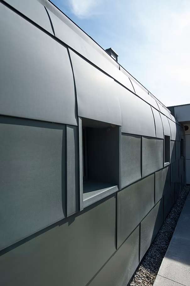 Nahaufnahme einer Hausfassade aus grauen Panelen.