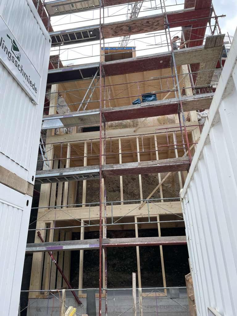 Baugerüst beim Aufbau eines Holzanbaus aus mehreren Holzbalken.