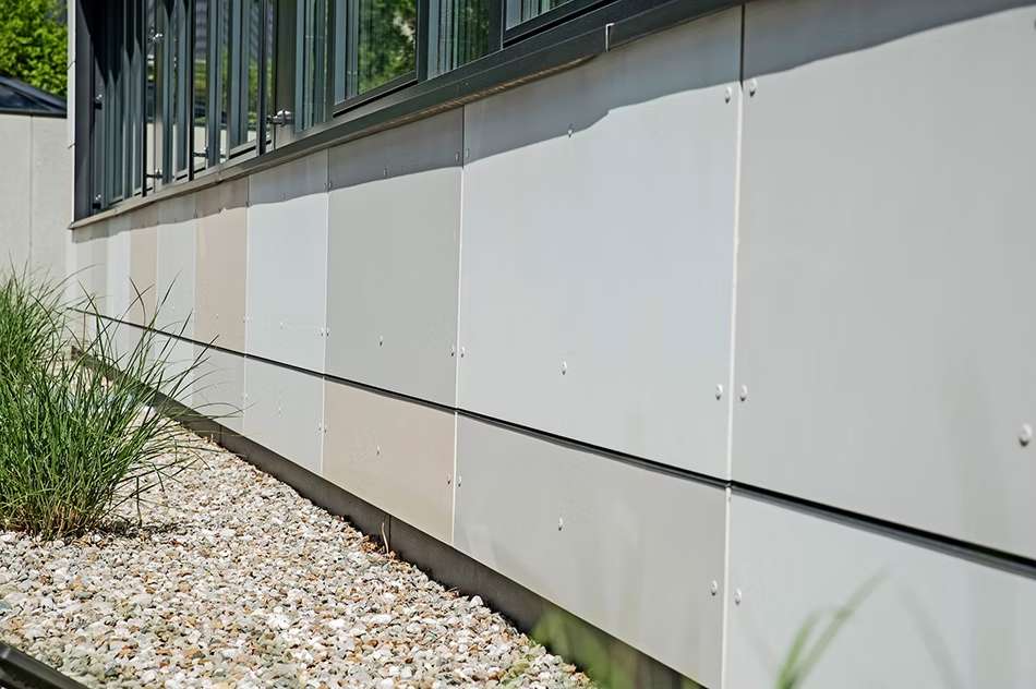 Nahaufnahme einer Fassade aus mehreren Platten in beige und grau.