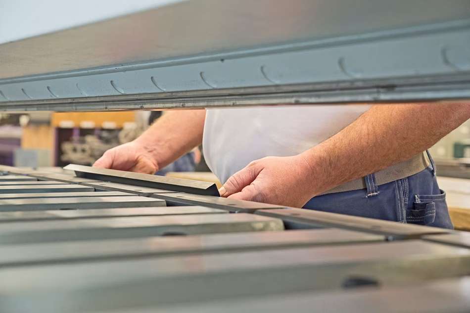 Ansicht durch die Maschine auf Handwerkerhände, die an Material arbeiten.