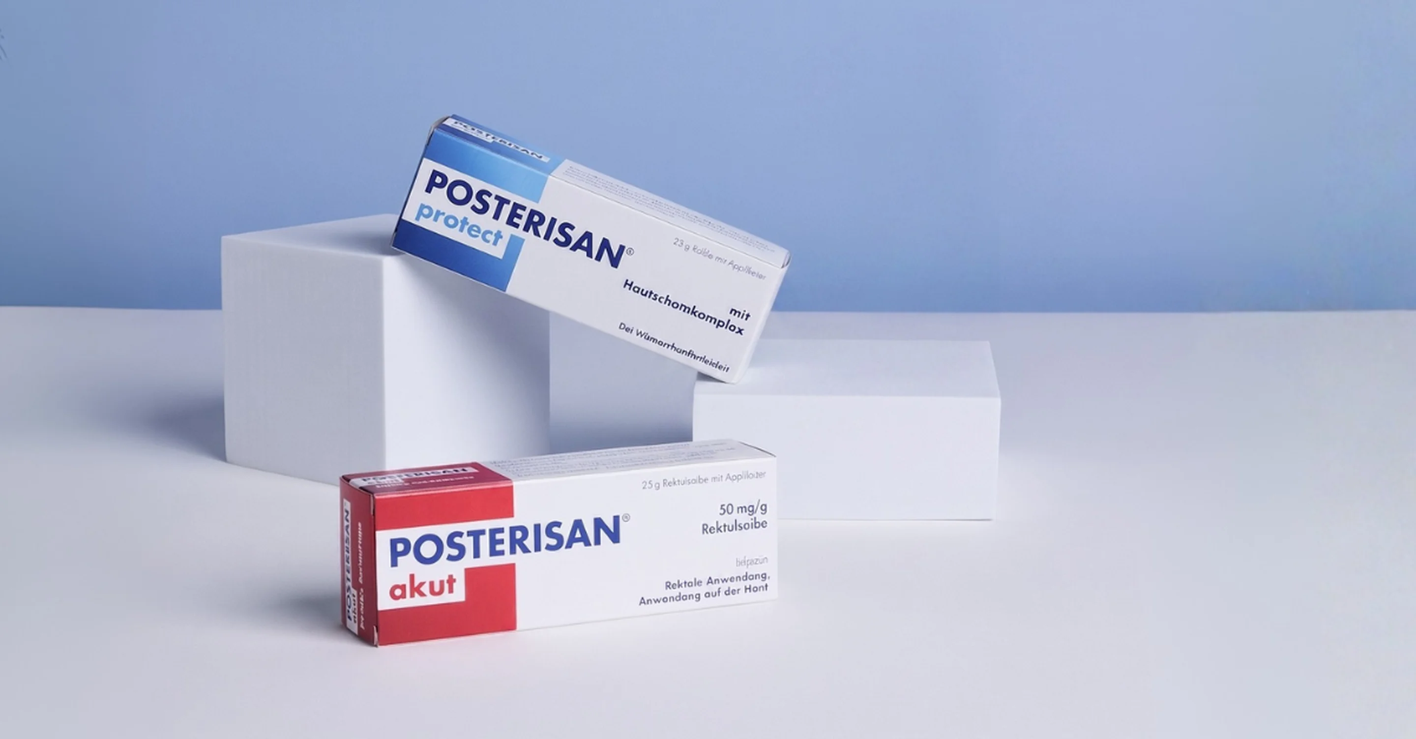 Verpackungen von Posterisan protect und Posterisan akut auf weißen Podesten vor blauem Hintergrund.