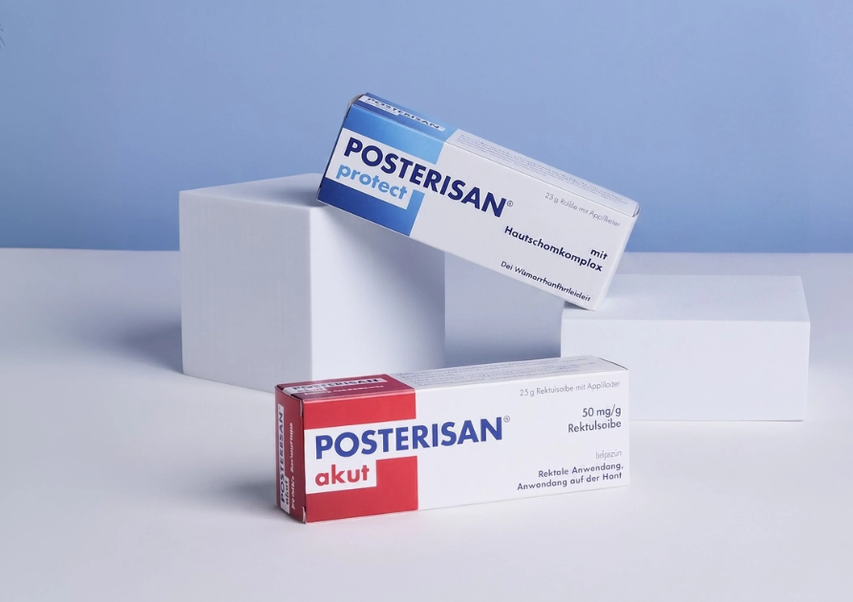 Verpackungen von Posterisan protect und Posterisan akut auf weißen Podesten vor blauem Hintergrund.
