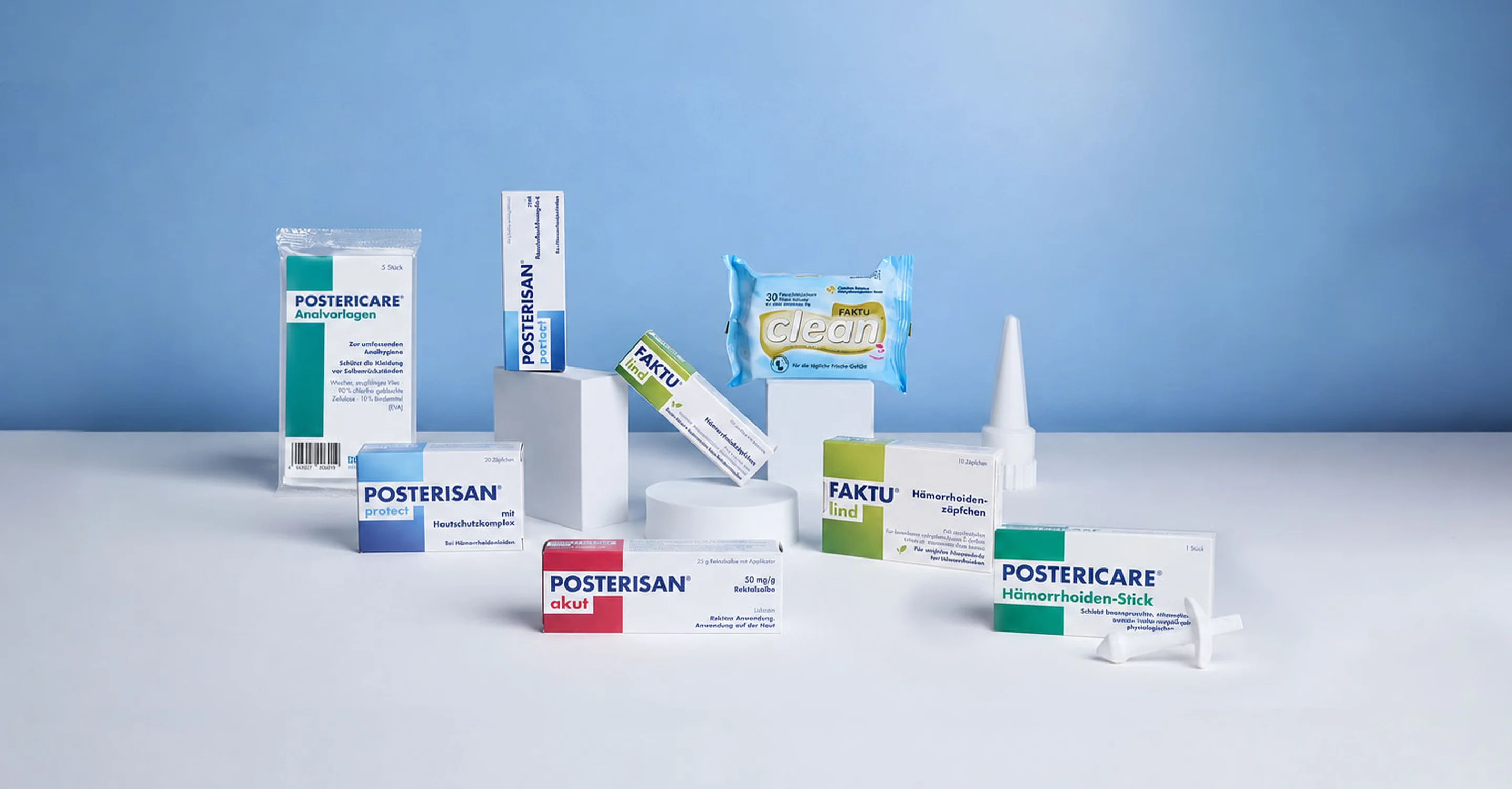 Posterisan akut, Posterisan protect Hämorrhoidensalbe und -zäpfchen, Faktu Lind Hämorrhoidensalbe und -zäpfchen, Posterisan Analvorlagen, Faktu Clean Pflegetücher und Postericare Hämorrhoiden-Stick auf einer weißen Fläche arrangiert.