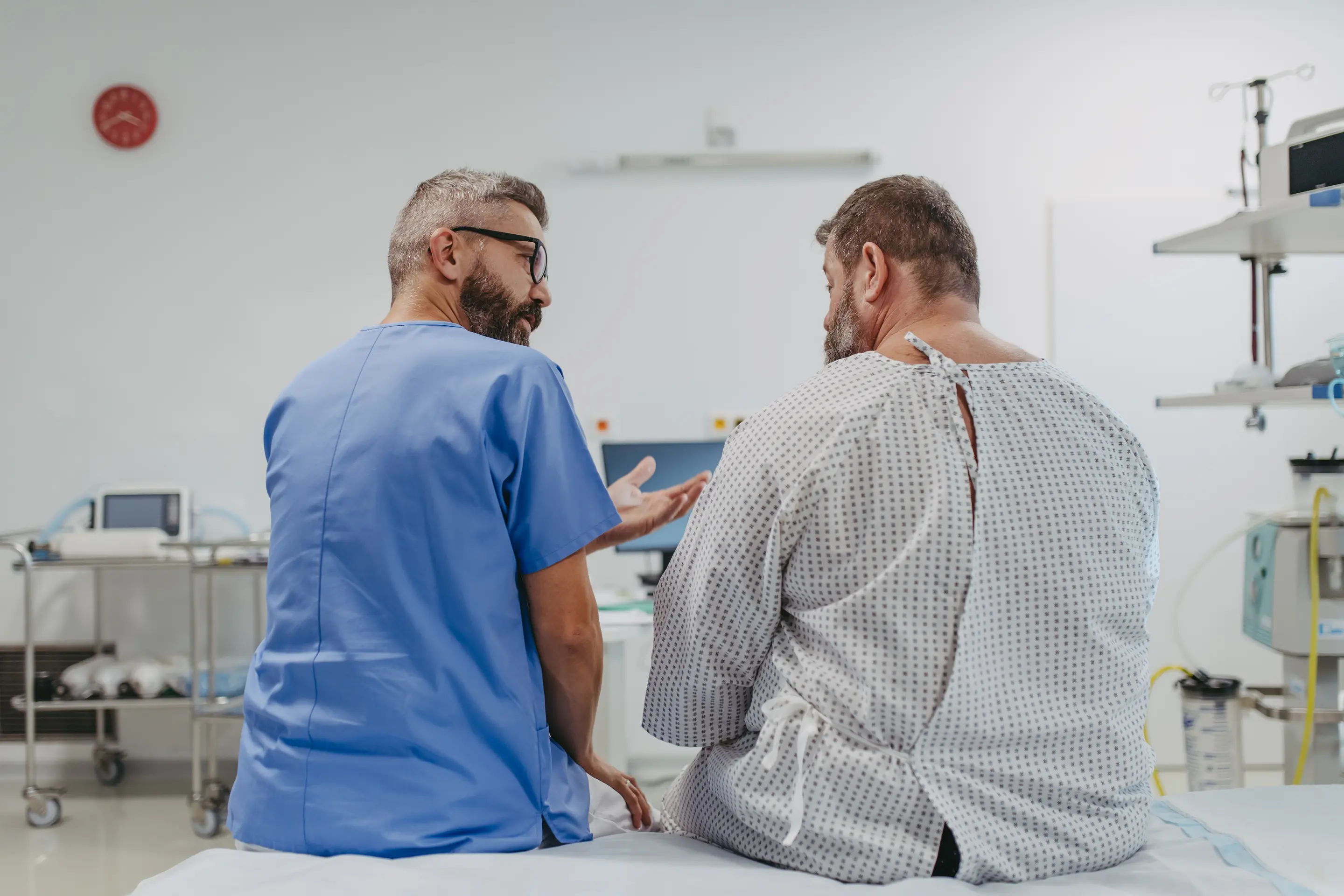 Eine medizinische Fachkraft sitzt neben einem Patienten und bespricht mit ihm eine Hämorrhoiden-OP.