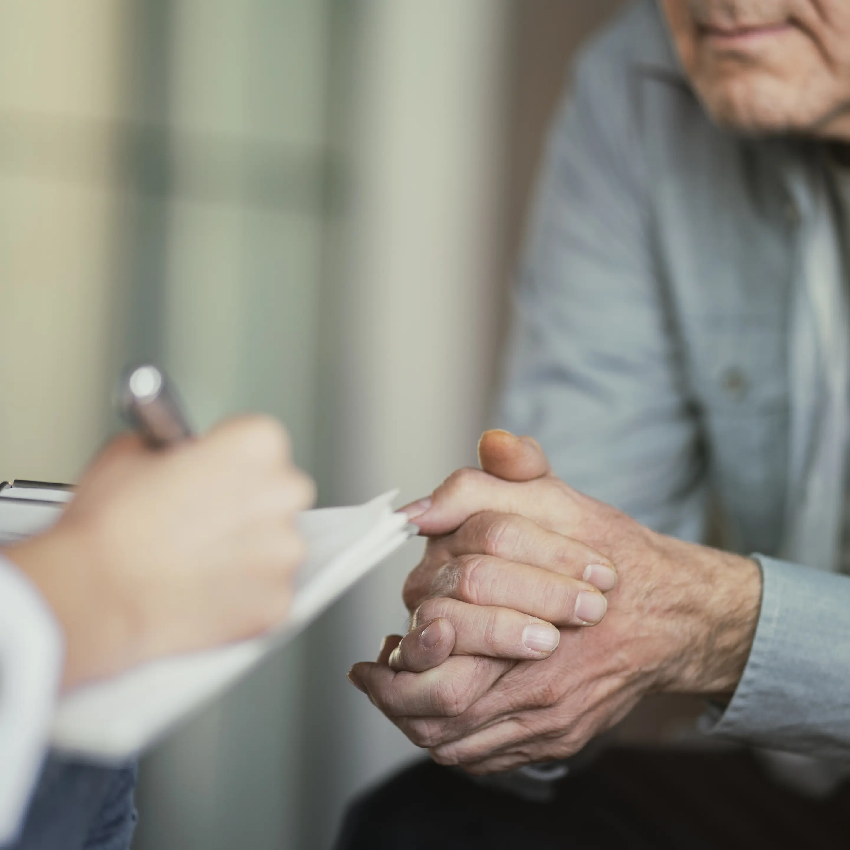 Ein älterer Patient im Gespräch mit einer medizinischen Fachkraft, die Notizen macht.