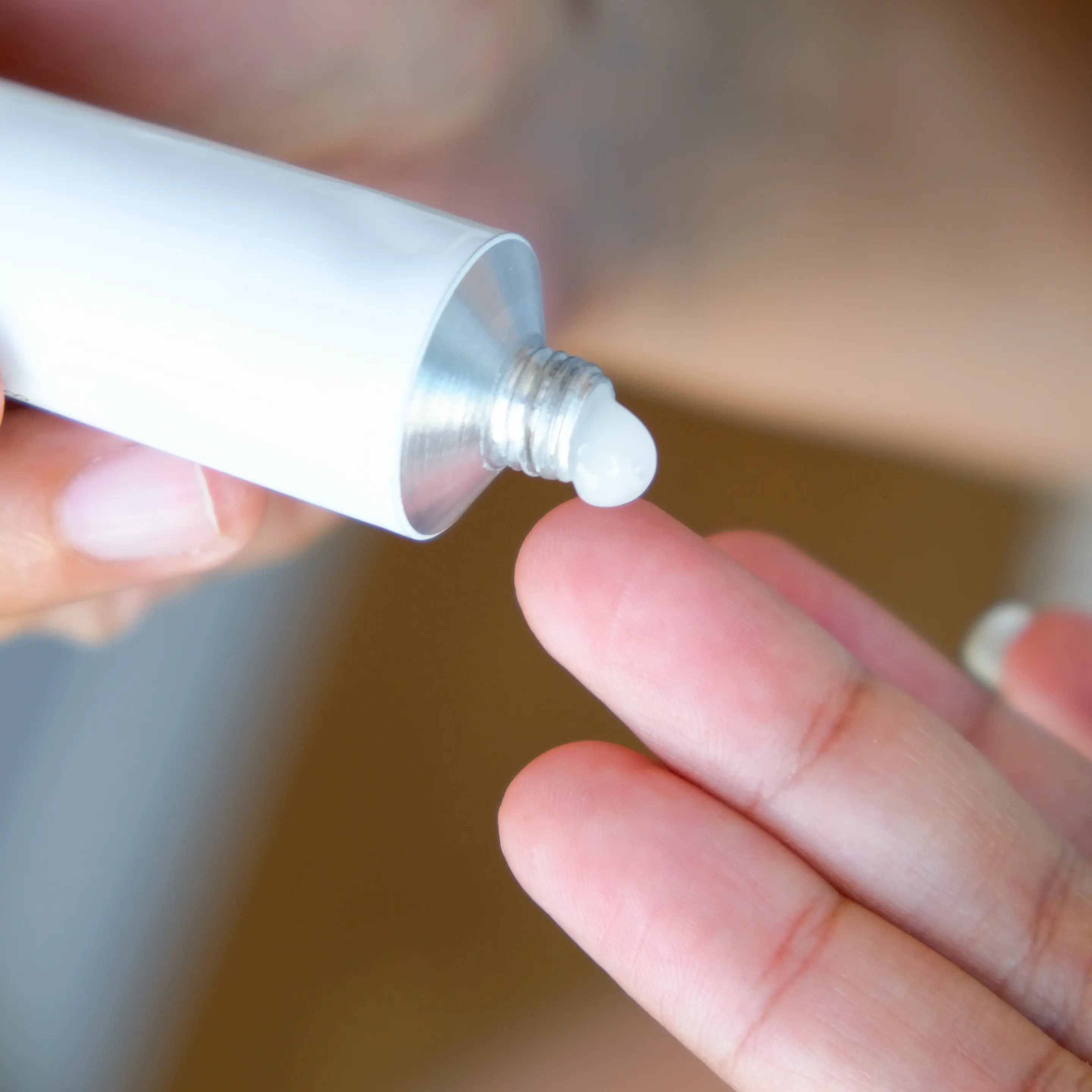 Eine Hand drückt aus einer Tube etwas Hämorrhoiden-Salbe mit Lidocain auf die Fingerspitze der anderen Hand.