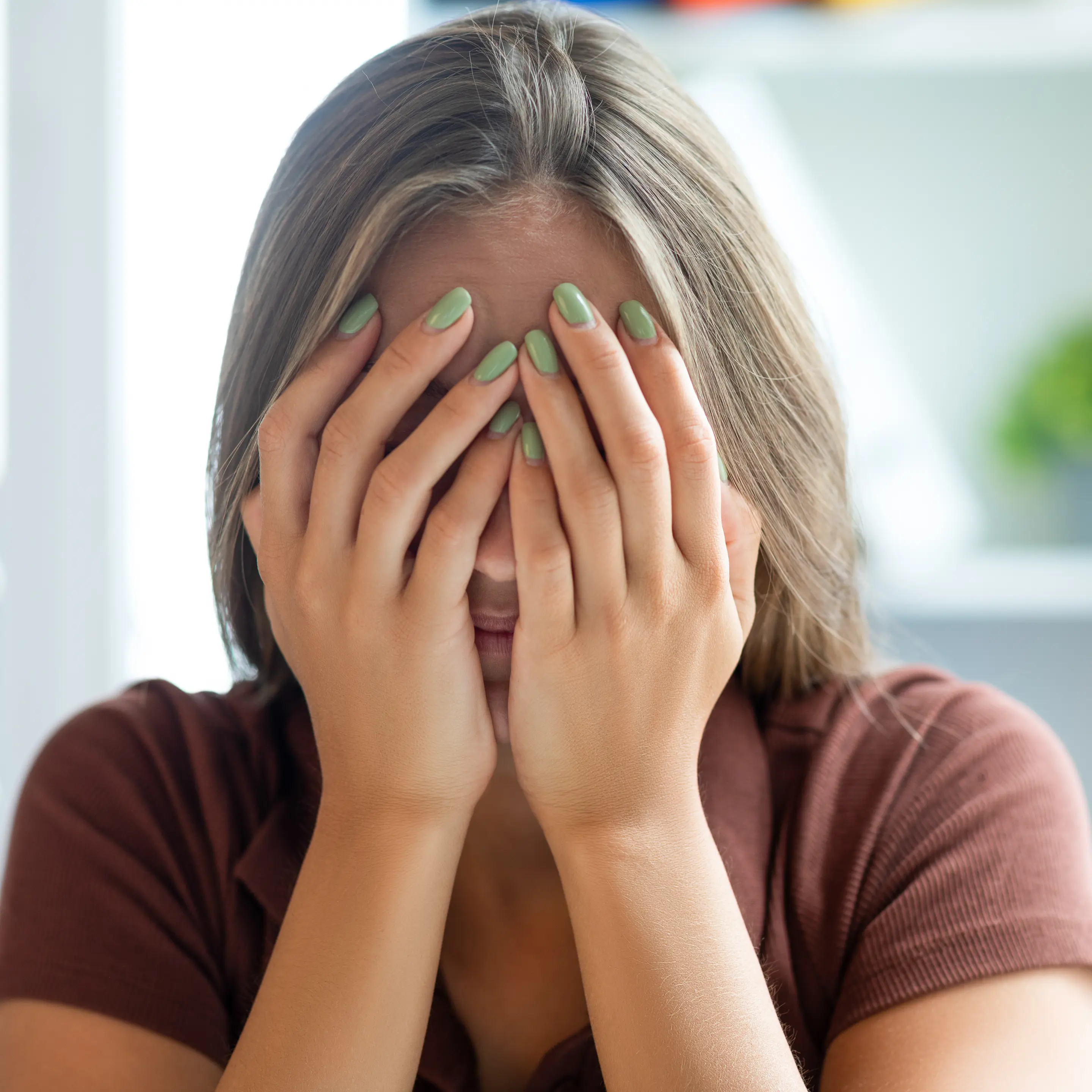Frau hält sich mit beiden Händen das Gesicht